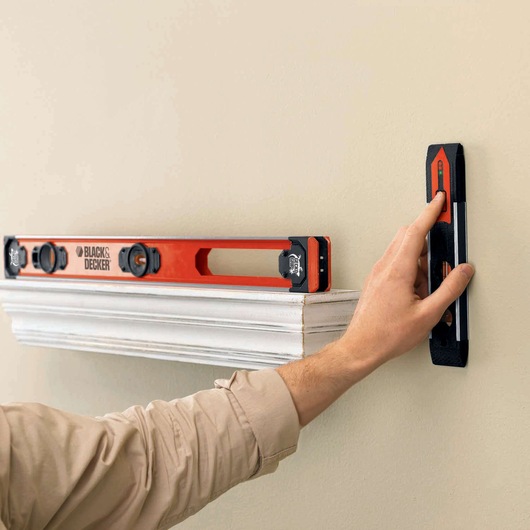BLACKDECKER BDSL30 level tool used to align shelf on beige wall, close-up of product in action.