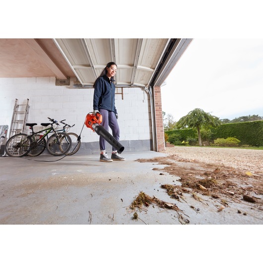 BLACKDECKER BEBL185 leaf blower used in garage to clear debris, outdoor context with bicycles visible.