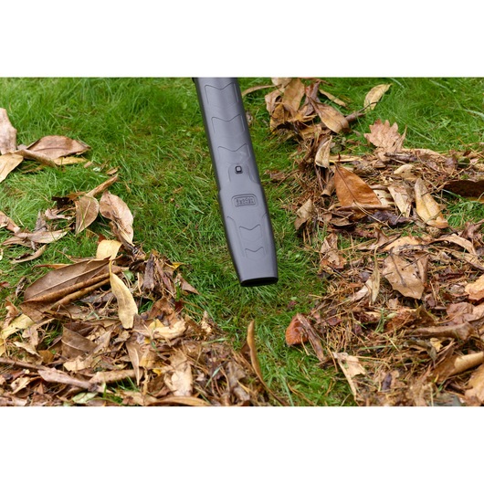 BLACKDECKER BEBLV301 leaf blower nozzle clearing dry leaves on grass, close-up outdoor view.