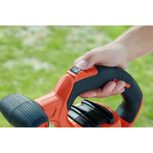 BLACKDECKER BEBLV301 leaf blower handle close-up with hand on black and orange grip, showing control switch.