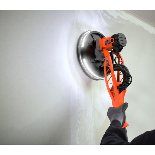 BLACKDECKER BEDW700A8S drywall sander with LED ring, being used on a wall, close-up angle.