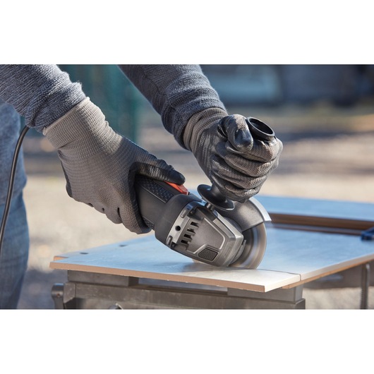 BLACKDECKER BEG220 angle grinder used to cut tile, close-up of hands wearing gloves.