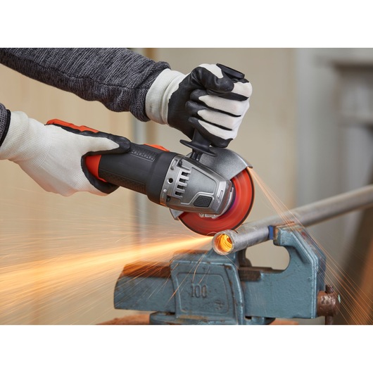 BLACKDECKER BEG220 angle grinder cutting metal pipe, close-up with safety gloves, sparks flying.
