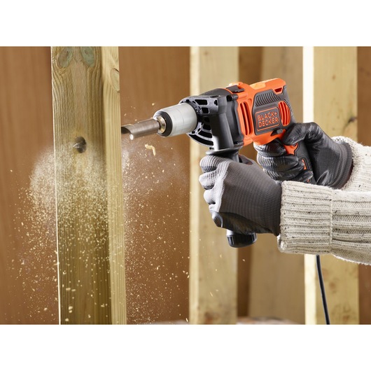 BLACK+DECKER BEH850K hammer drill used to bore a hole in wood, dust flying, close-up action.