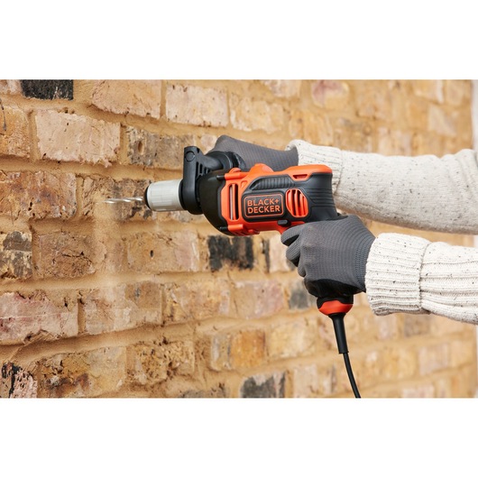 BLACKDECKER BEH850K corded hammer drill in use drilling into brick wall, close-up view.