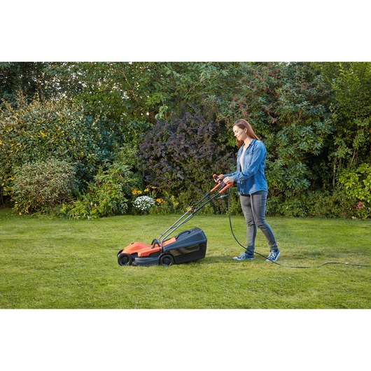 BLACKDECKER BEMW451BH lawn mower in use on grass in a garden setting.