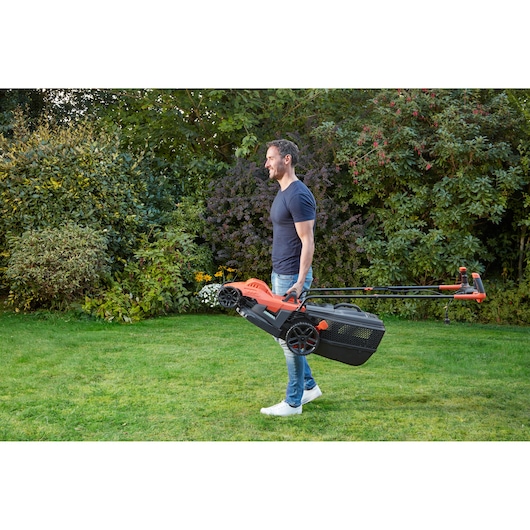 BLACKDECKER BEMW461BH lawn mower with handle, carried by person in garden.