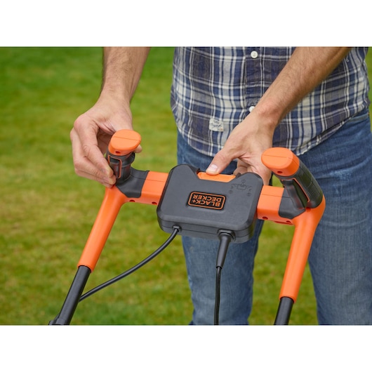 Photo of BLACK+DECKER BEMW461BH lawn mower handle controls held by a person outdoors.