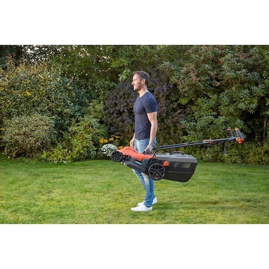 BLACKDECKER BEMW461ES lawn mower carried by person in garden, side view.
