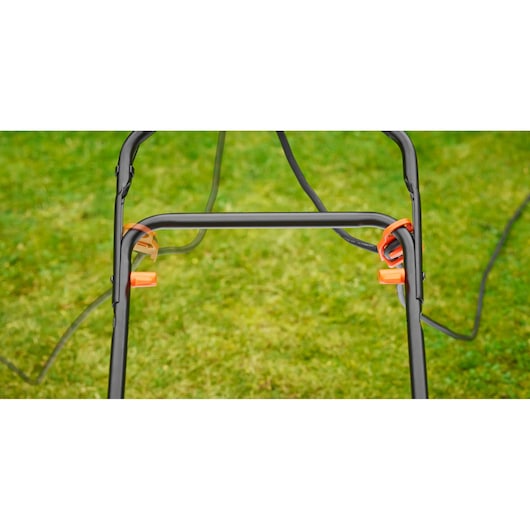 BLACKDECKER BEMW471ES lawn mower handle with orange lever and cable, close-up on grass.