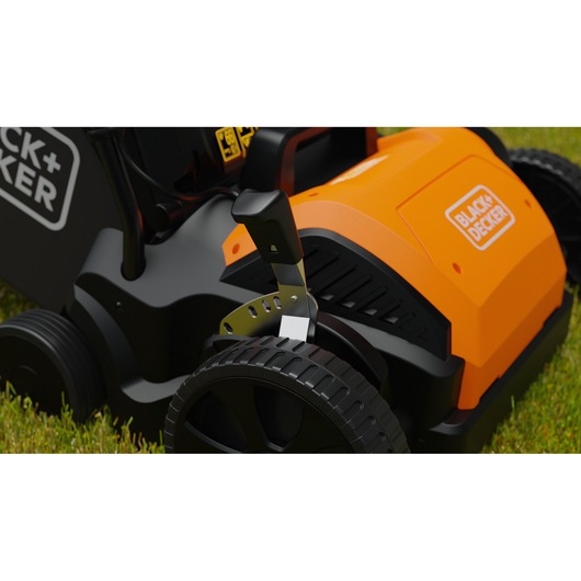 Photo of BLACK+DECKER BEOEP320-QS lawn mower close-up, showing orange housing and height adjustment lever on grass.