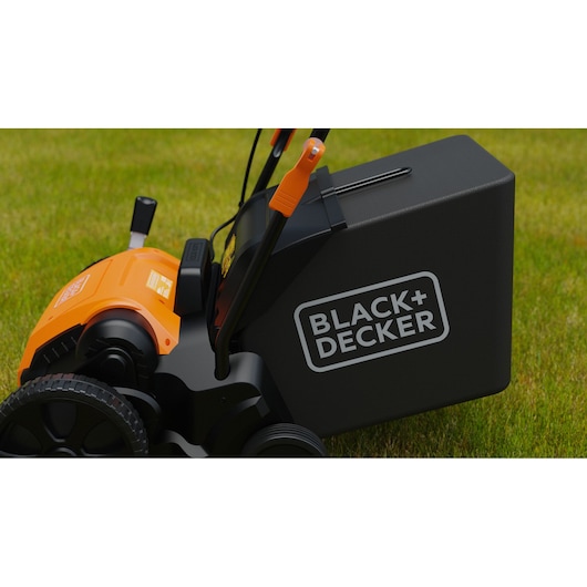 Photo of BLACK+DECKER BEOEP320-QS electric lawn mower side view on grass, showing black grass box and orange housing.