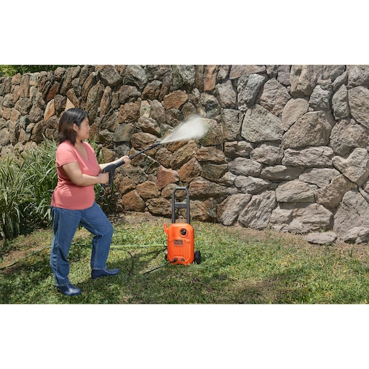 BLACKDECKER BEPW1650 pressure washer cleaning a stone wall outdoors.
