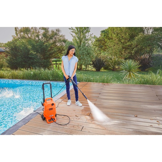 BLACKDECKER BEPW1700 pressure washer cleaning poolside wooden deck outdoors.