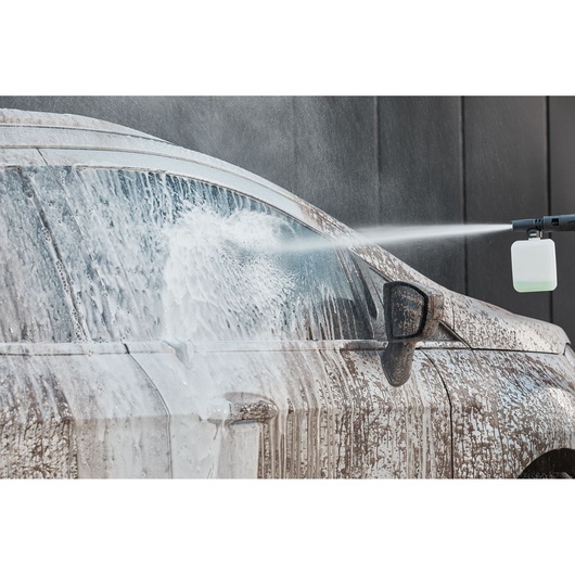 BLACKDECKER BEPW2000 power washer spraying foam on a dirty car, front side view.