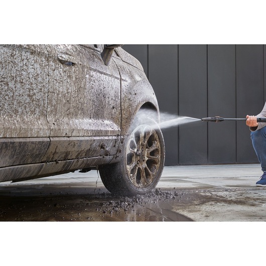 BLACKDECKER BEPW2000 pressure washer cleaning muddy car wheel, photo shows water spray removing dirt.