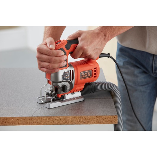 BLACKDECKER BES610K jigsaw cutting wood with dust extraction hose, handheld close-up photography.