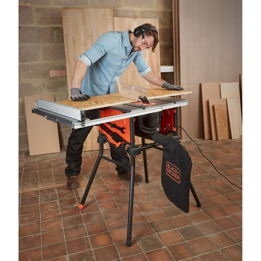 BLACKDECKER BES720 table saw with dust bag, cutting wood in workshop setting.