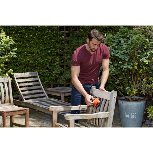 BLACKDECKER BEW200LSA sander used on outdoor wooden chair in garden setting.