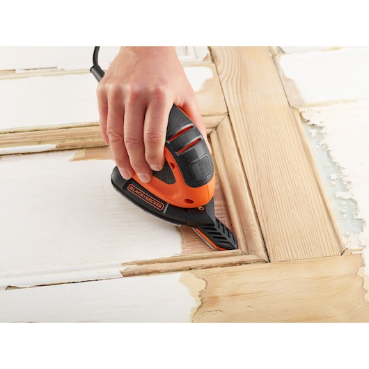 BLACK+DECKER BEW230BCES detail sander being used to remove paint from a wooden door surface.