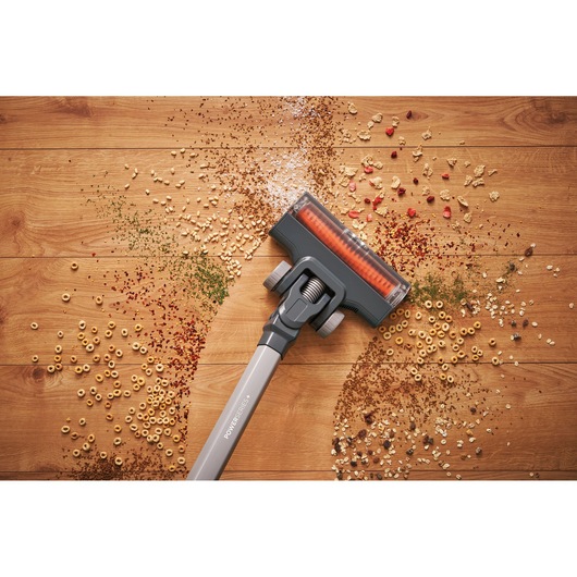 BLACKDECKER BHFEA18D1 cordless vacuum head cleaning assorted debris on wood floor, top view.