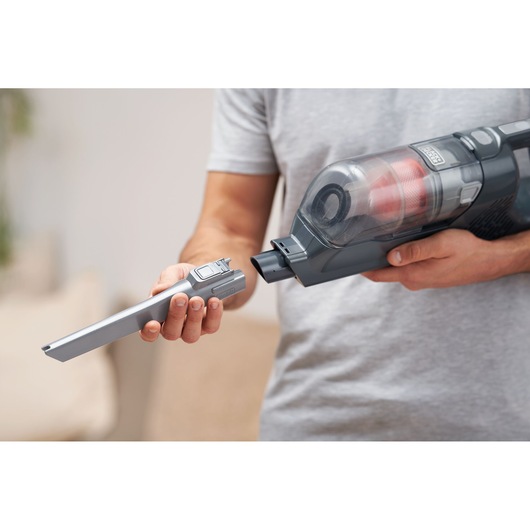 BLACKDECKER BHFEA18D1 cordless vacuum cleaner with crevice tool attachment held by person indoors.