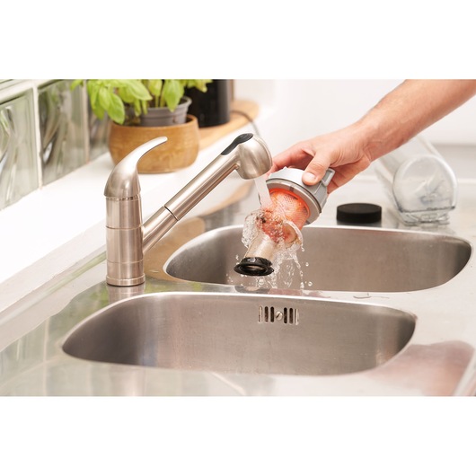 BLACKDECKER BHFEA18D1 vacuum filter being rinsed under kitchen faucet over stainless steel sink.