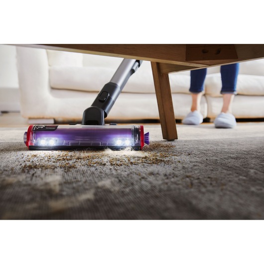 BLACKDECKER BHFEA640WP cordless vacuum cleaning under a table on a carpet with LED lights on the floor tool.