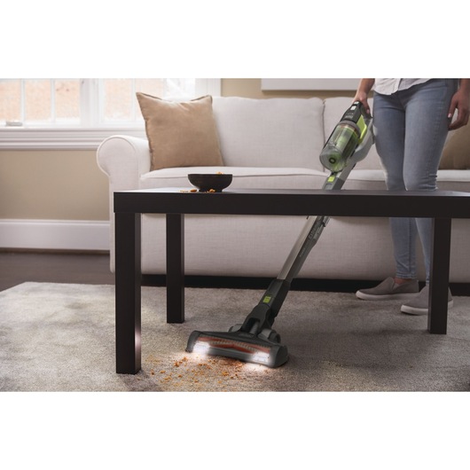 Photo of BLACKDECKER BHFEV362DA cordless vacuum cleaning crumbs from carpet in living room under coffee table.