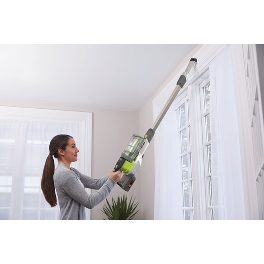 BLACKDECKER BHFEV362DA cordless vacuum cleaner with extension cleaning tool used near a window.