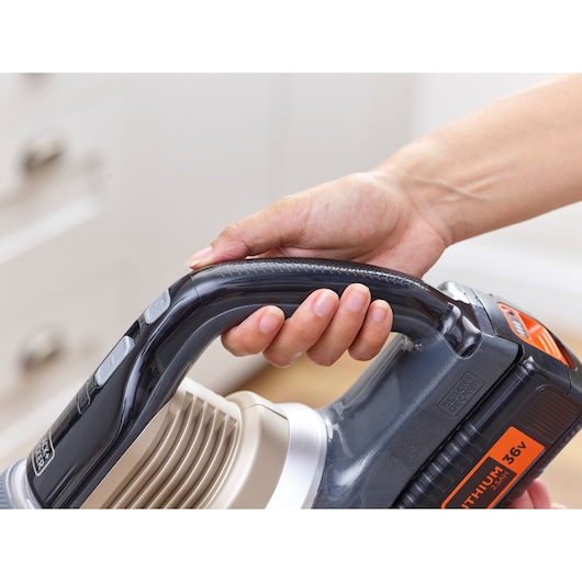 Close-up of a hand holding the handle of a BLACK+DECKER 35V lithium cordless vacuum cleaner.