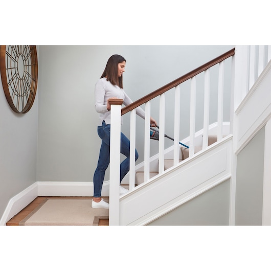 BLACKDECKER BHHV320J handheld vacuum used on carpeted stairs in a home interior.