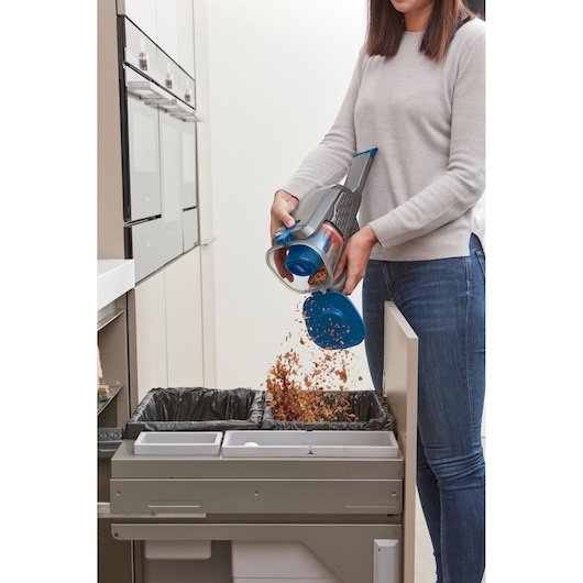 BLACKDECKER BHHV320J handheld vacuum being emptied into kitchen trash bin.