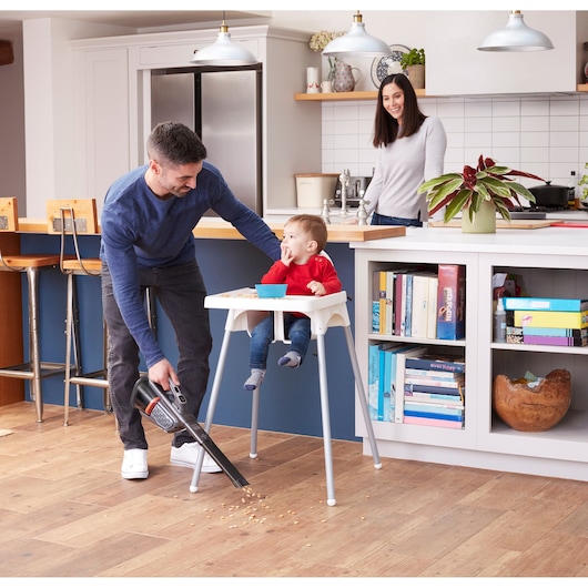 BLACKDECKER BHHV520JF handheld vacuum cleaning food debris by high chair in modern kitchen.