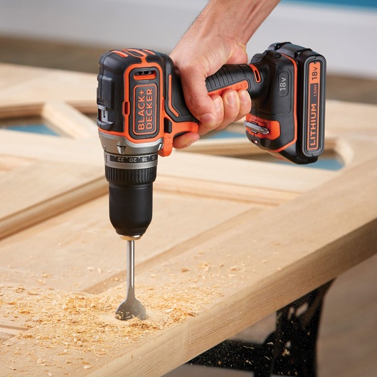 BLACKDECKER BL186KB cordless drill in use on wood, showing orange and black design and 18V lithium battery