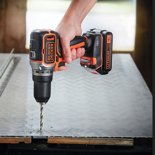 BLACKDECKER BL186N cordless drill being used to drill into metal sheet, close-up view.