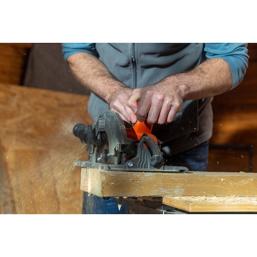 BLACKDECKER BLCCS78E1 circular saw cutting wood, close-up of hands operating tool, wood dust flying.