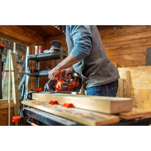 BLACKDECKER BLCCS78M1 cordless circular saw used on wood in a workshop, side angle.
