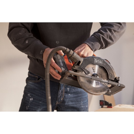 BLACK+DECKER BLCCS78M1 circular saw in use, cordless with dust extraction hose attached.
