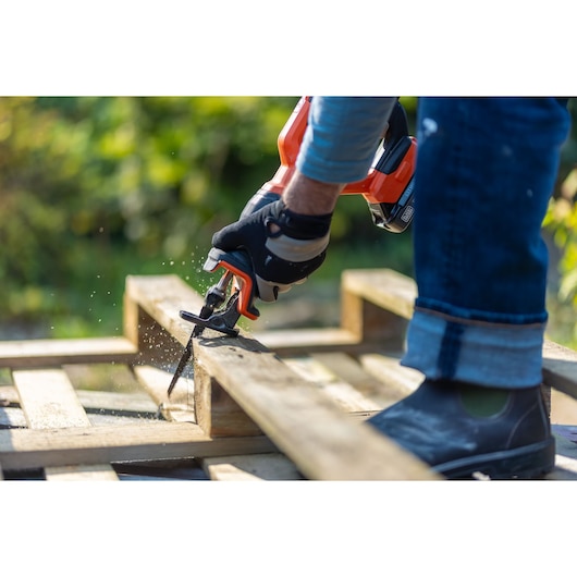 BLACKDECKER BLCR78E1 reciprocating saw cutting wood outdoors, close-up of gloved hand and tool.