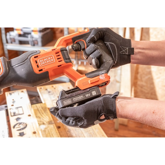 BLACK+DECKER BLCR78E1 reciprocating saw with 18V battery, close-up, hands wearing work gloves.