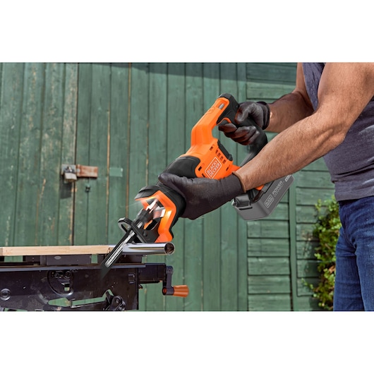 BLACKDECKER BLCR78M1 reciprocating saw with black and orange grip cutting metal pipe outdoors.