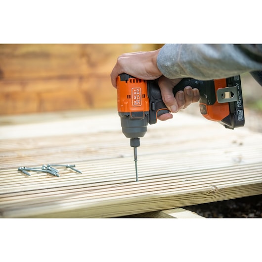 BLACKDECKER BLIM78E1K cordless impact driver in use, driving a screw into wooden decking.