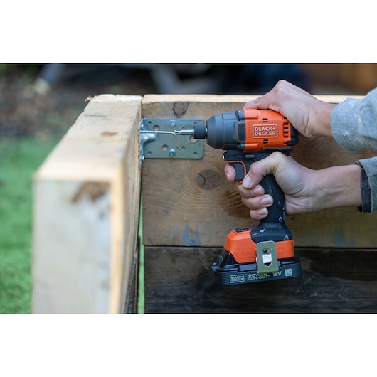 BLACKDECKER BLIM78E1K cordless impact driver used to fasten screw in wooden structure outdoors.