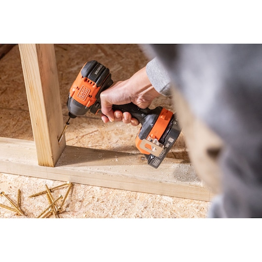 BLACKDECKER BLIM78E1K cordless impact driver used to drill screw into wooden frame, close-up action shot.