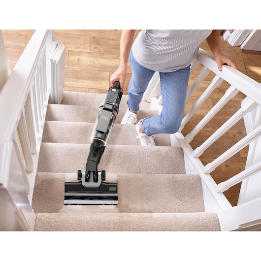 Photo of BLACKDECKER BSV520BL2P cordless stick vacuum cleaning carpeted stairs.