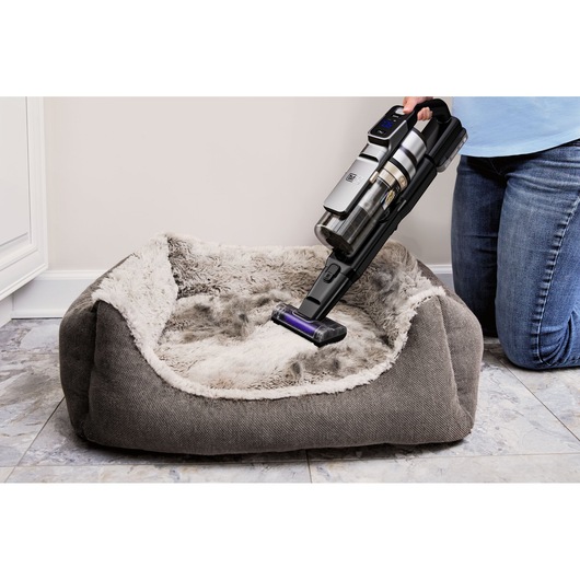 BLACKDECKER BSV525BLP cordless vacuum cleaning a gray pet bed, close-up angle.
