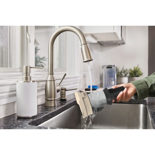 BLACKDECKER BSV525BLP vacuum filter being rinsed under a kitchen faucet in a modern kitchen.