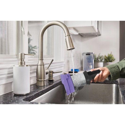 Photo of BLACKDECKER BSV525BRP vacuum filter being rinsed under a kitchen faucet in a sink.