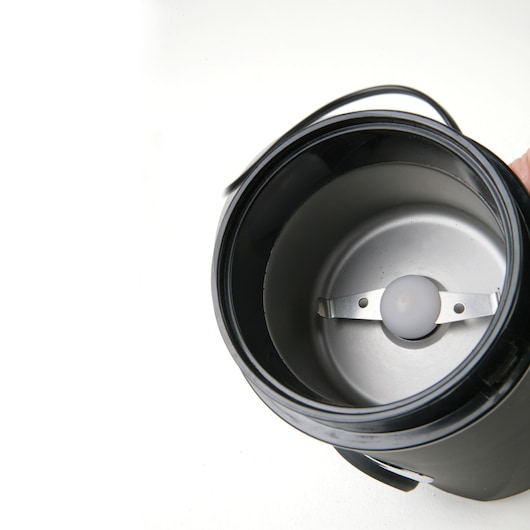 BLACKDECKER BXCG150E coffee grinder inner chamber with stainless steel blade, top view, white background.